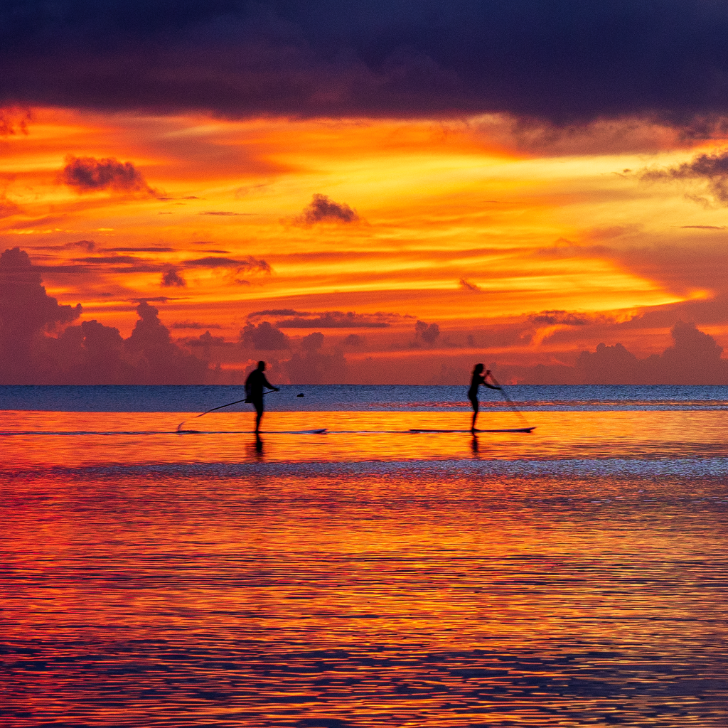 Enlarged detail of the Tumon Bay Sunset print, highlighting the sharp silhouettes of paddleboarders on the water.