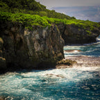 A close-up view highlighting the sharp, porous texture of coastal volcanic limestone formations against churning blue seawater.