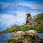 A close-up view focusing on the weathered limestone textures of the iconic Bear Rock formation rising above tropical coastal foliage.