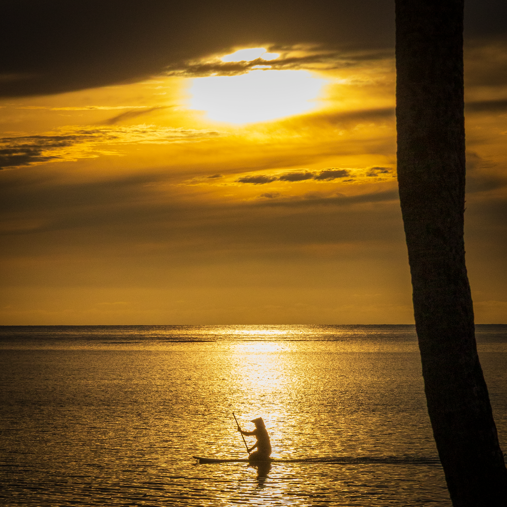 A close-up view highlighting the intense orange and gold light reflecting off subtle ripples on the water's surface at sunset.