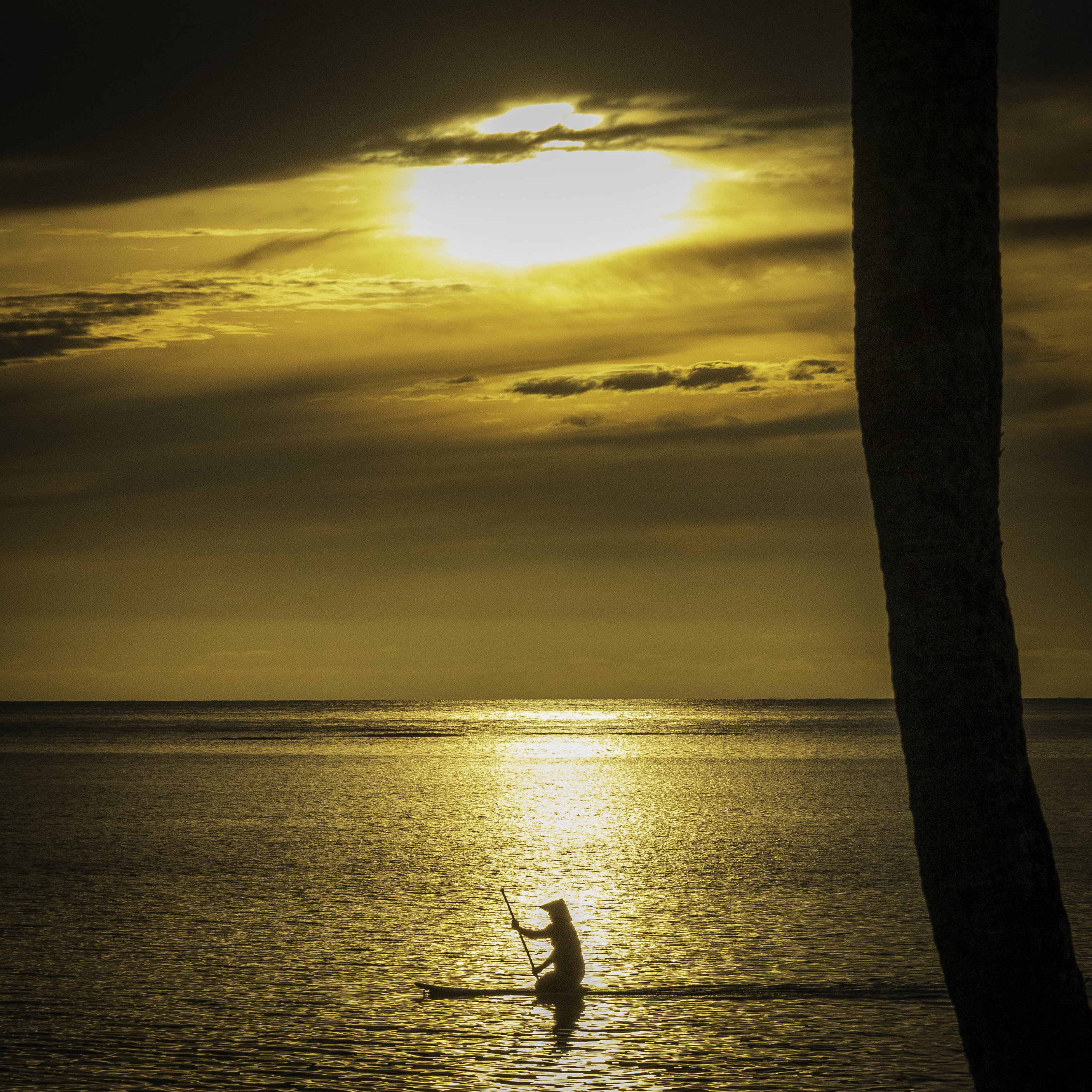 A close-up view highlighting the intense orange and gold light reflecting off subtle ripples on the water's surface at sunset.
