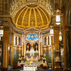 A close-up architectural detail shot of the intricate golden altarpiece and ornate carvings inside St. Jean Baptiste Church.