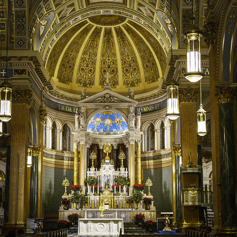 A close-up architectural detail shot of the intricate golden altarpiece and ornate carvings inside St. Jean Baptiste Church.