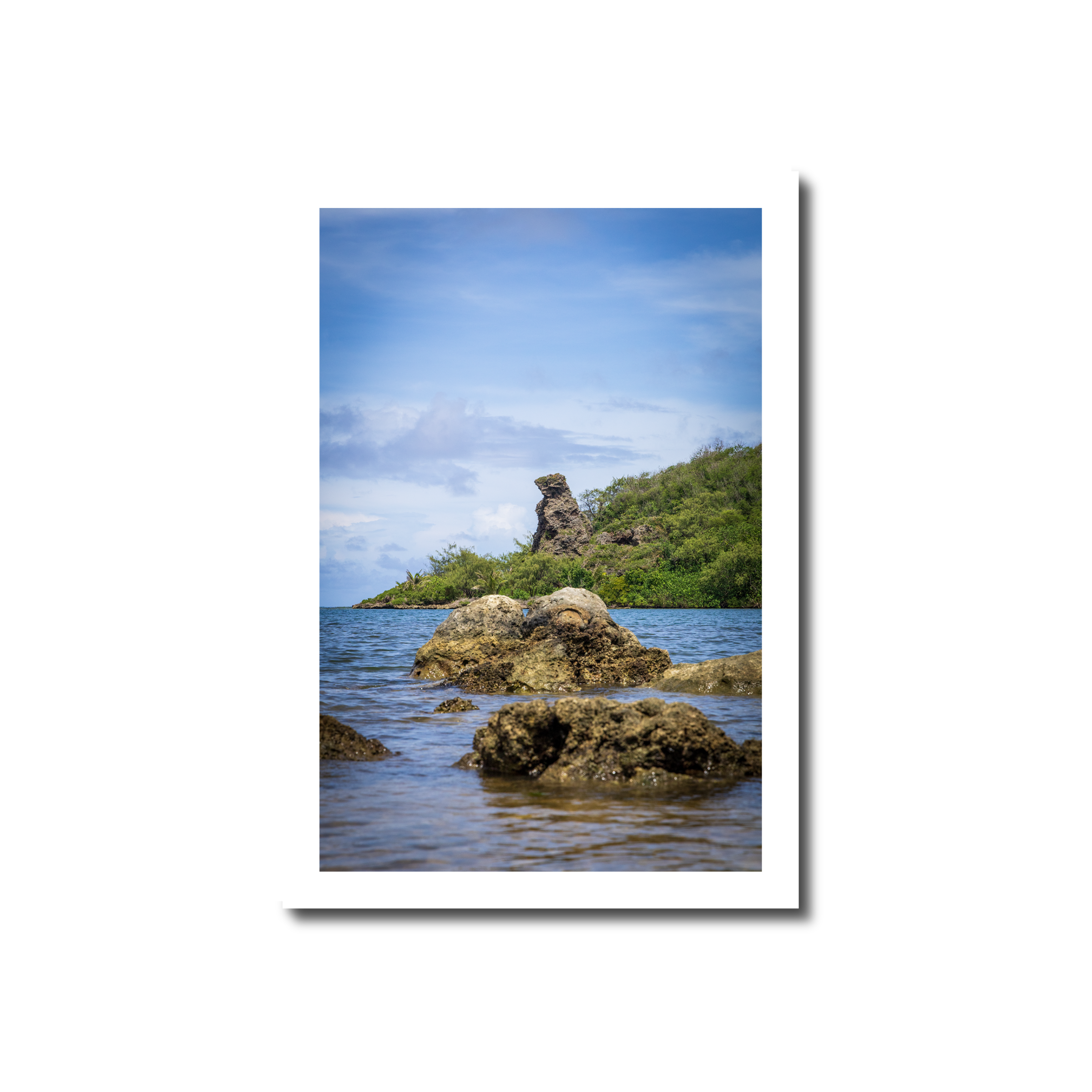 Coastal landscape photograph of Bear Rock formation standing along the lush green shoreline of Inalåjan Bay in Guam.