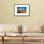A framed landscape photography print of Big Sable Point Lighthouse displayed on a modern living room wall over a couch.