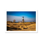 Landscape view of the historic black and white Big Sable Point Lighthouse rising above rolling golden sand dunes in Michigan.