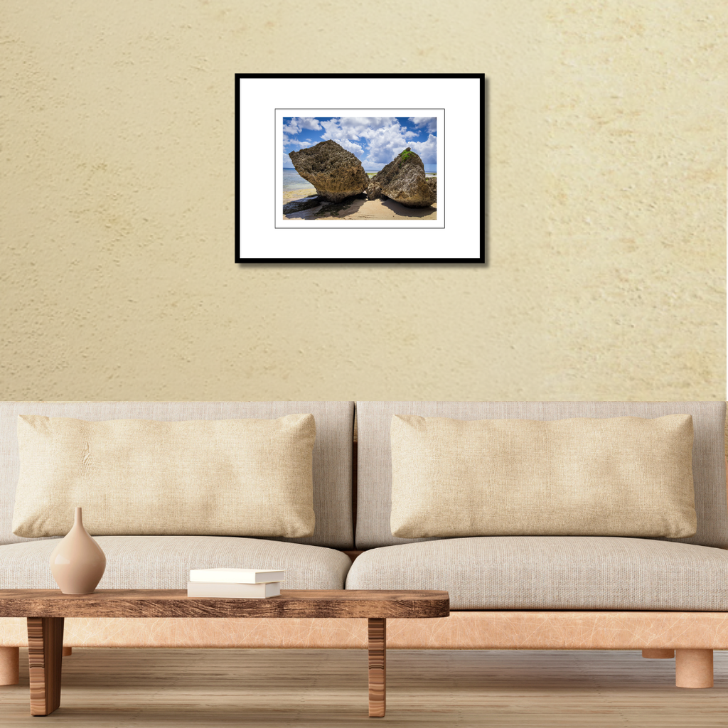 A 18x12 Gun Beach Rocks print in an 24x18 frame, styled on a living room wall above a contemporary couch.