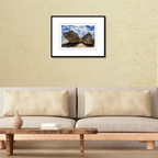 A 18x12 Gun Beach Rocks print in an 24x18 frame, styled on a living room wall above a contemporary couch.
