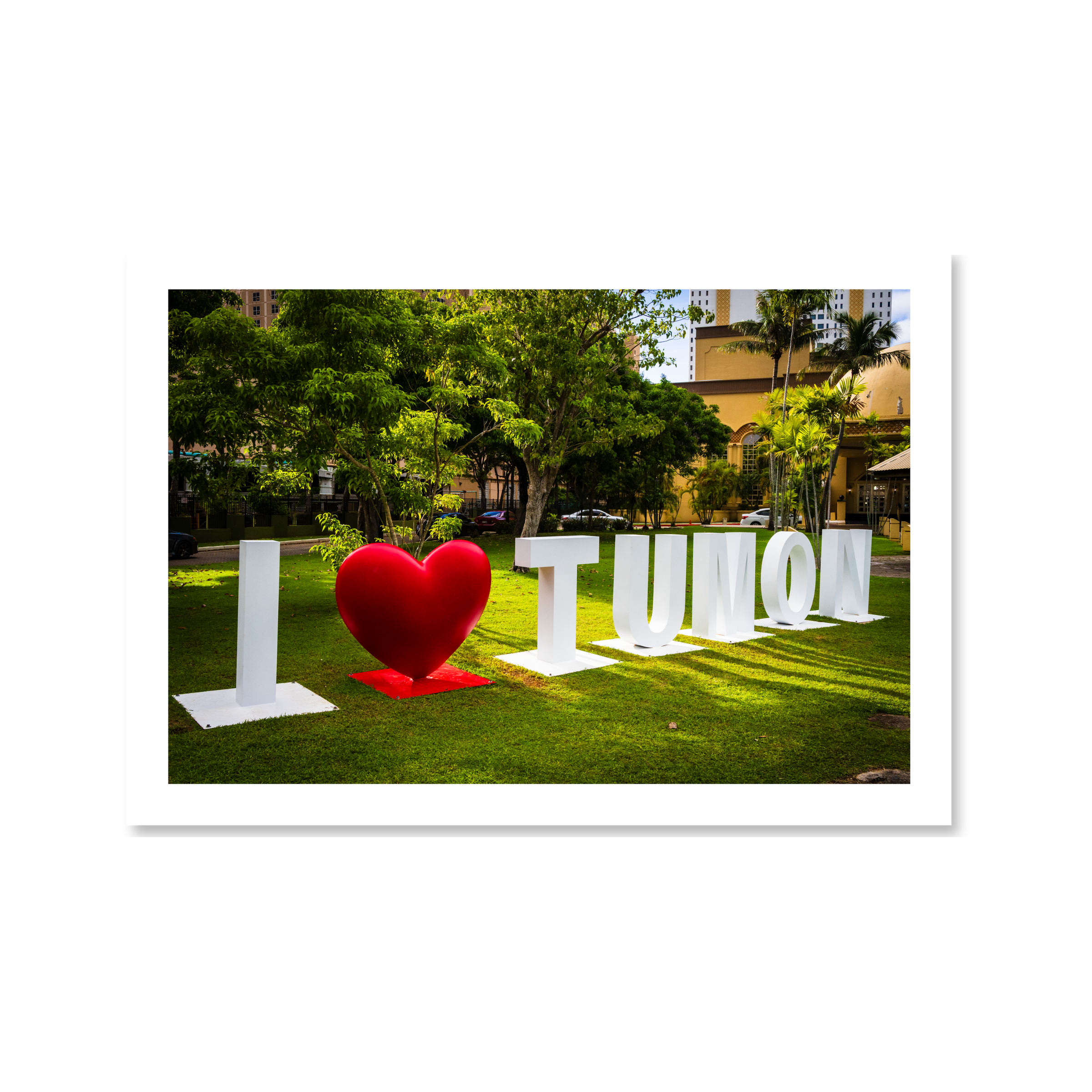 Large white letters and a bold red heart spelling out I Love Tumon on a sunny green lawn in Tumon, Guam.