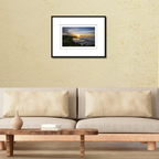 A framed fine art print of the Inalåjan natural tide pools at sunrise displayed on a wall over a modern couch to show scale.