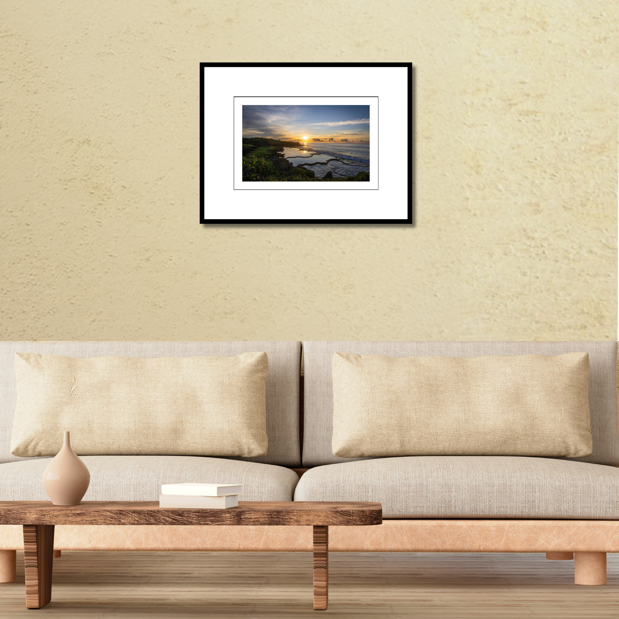 A framed fine art print of the Inalåjan natural tide pools at sunrise displayed on a wall over a modern couch to show scale.