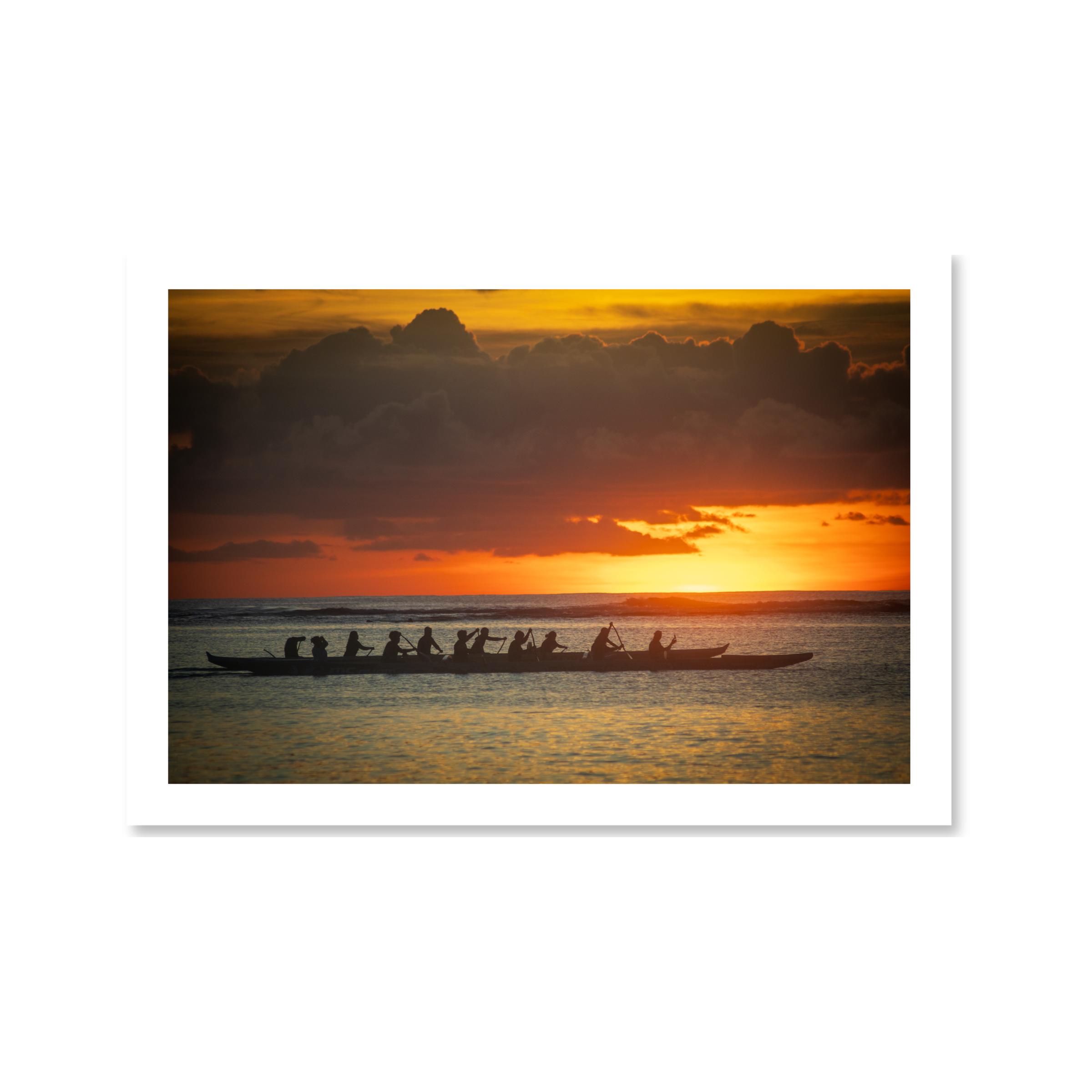 A striking silhouette of a traditional outrigger canoe team paddling across calm ocean waters during a vibrant golden sunset.