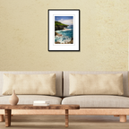 A framed landscape photography print of the Pagat Point coast displayed on a gallery wall over a modern credenza to show scale.