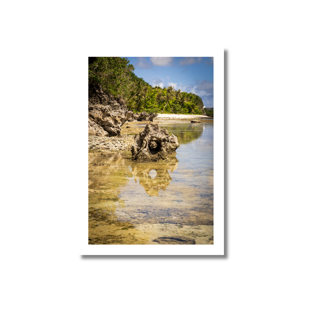 A symmetrical fine art photograph capturing a dramatic rock formation perfectly reflected in the still, clear waters of a Guam tide pool.