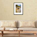A framed landscape print of a coastal reflection in Guam displayed on a living room wall over a modern shelf to demonstrate scale.