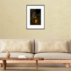 A framed fine art travel print of a carved tiki totem at night displayed on a living room wall above a modern couch to show scale.