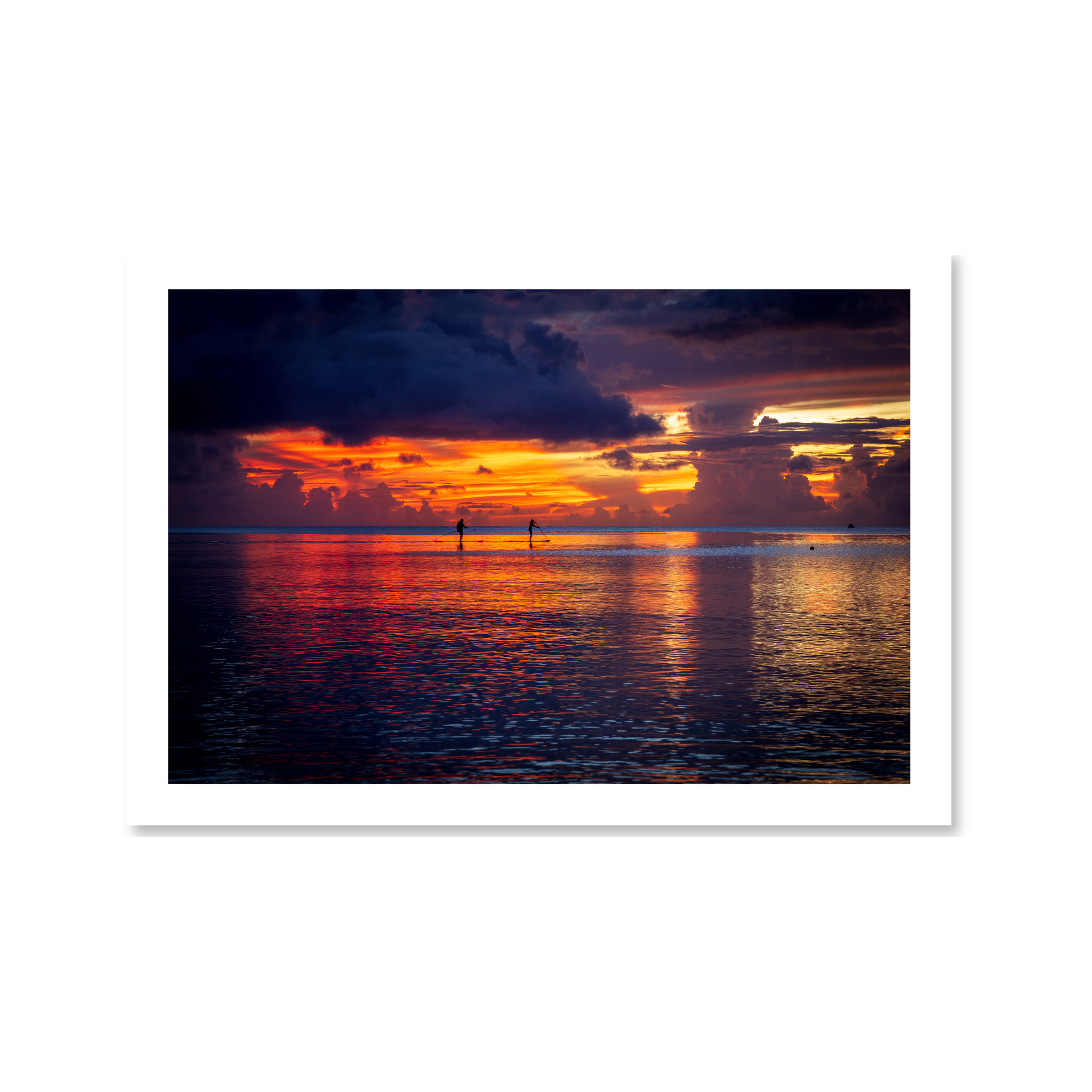 Fine art landscape photo of a sunset over Tumon Bay, Guam, with silhouettes of paddleboarders on the Philippine Sea.