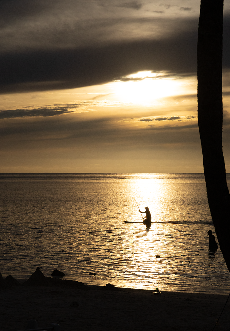 RAW - This sunset shows the diversity of the play of light with the clouds. Compare it to the next print Palm Tree Sunset, which was taken on the same night. Here you see a kneeling paddleboarder emerging from behind a slim palm tree to glide across the glowing path of the sun.